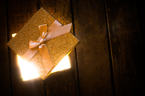 an open glowing gift box on wooden floor