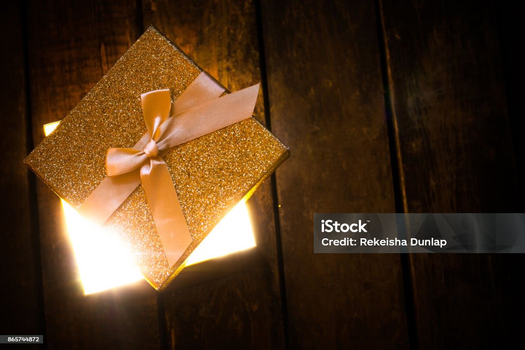 Golden glowing box of light an open glowing gift box on wooden floor Gift Stock Photo