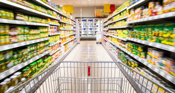 Shopping carts in the supermarket An empty shopping cart between rows of shelves in the supermarket. convenience food photos stock pictures, royalty-free photos & images