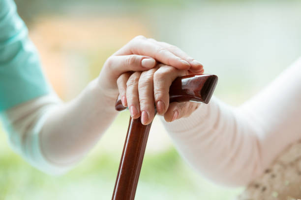 istock Senior holds hands on walking stick 865750874