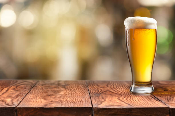 vaso de cerveza sobre la mesa de madera y fondo borroso. - beer beer glass isolated glass fotografías e imágenes de stock