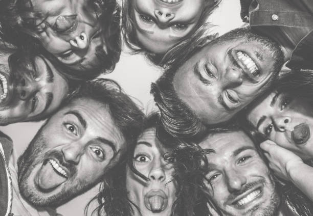 Bottom view of young friends making funny faces on camera - Happy people having fun making selfie  - Focus on top right man - Black and white editing - Friendship concept - Warm contrast filter