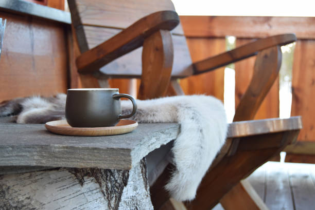 Coffee cup outside on mountain lodge porch Dark green coffee cup outside on mountain lodge porch with reindeer skins and chair. chalet stock pictures, royalty-free photos & images
