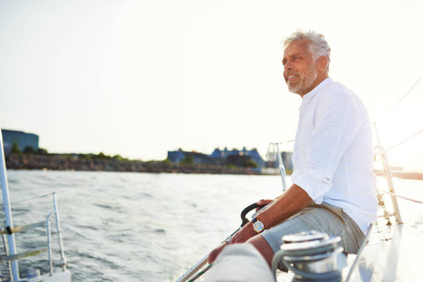 istock Smiling mature man out sailing on a sunny afternoon 865768480