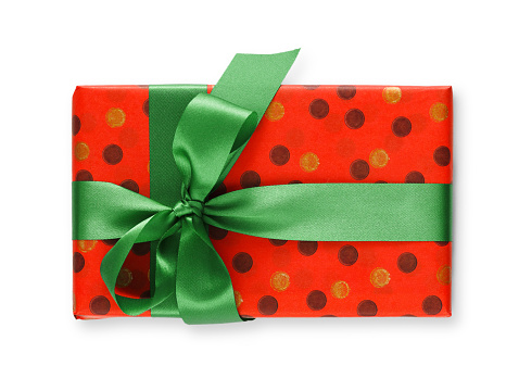 Gift box wrapped in dotted red paper and green satin ribbon, isolated on white background. Modern present for any holiday, christmas, valentine or birthday