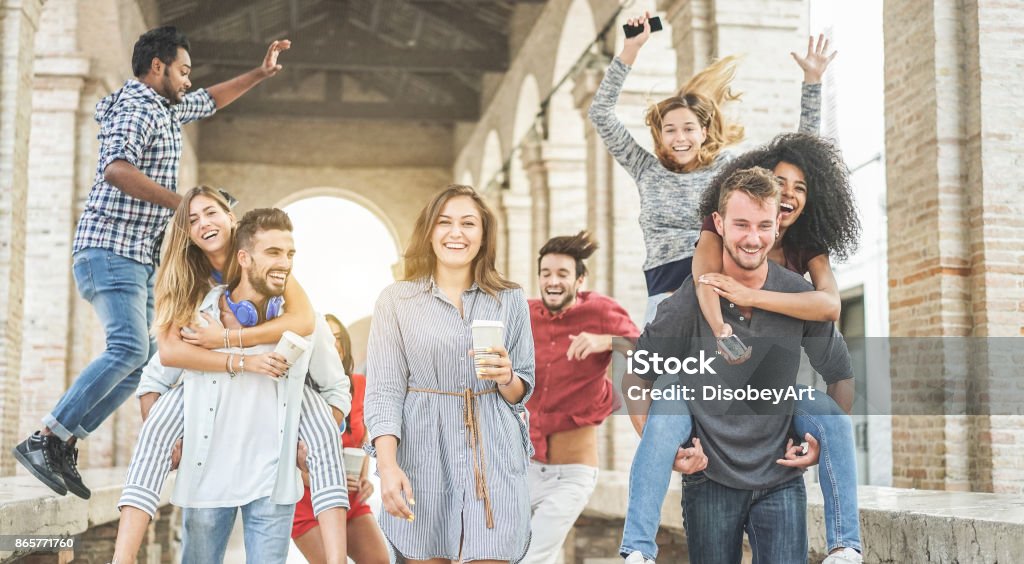 Happy students having fun in old city center - Young people at university break enjoying time together - Youth and positive mood with friends concept - Focus on center woman holding coffee paper cup Group Of People Stock Photo