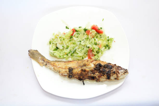 Fried fish on a white plate on the gas stove in the kitchen.