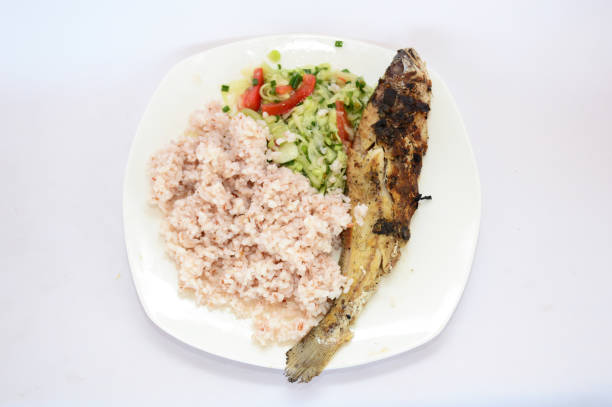 Grilled fish with white rice and cucumber salad and tomatoes.