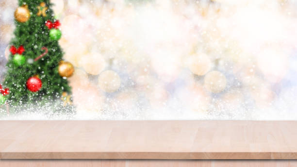 istock Wood table top on gold bokeh christmas tree background with snowfall. 865773418