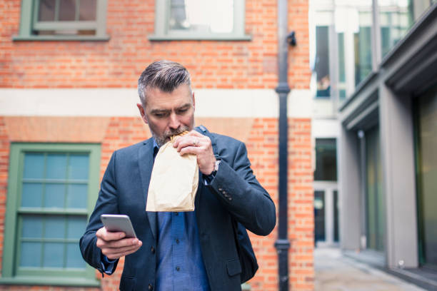 istock Businessman eating a sandwich and using smart phone 865779686