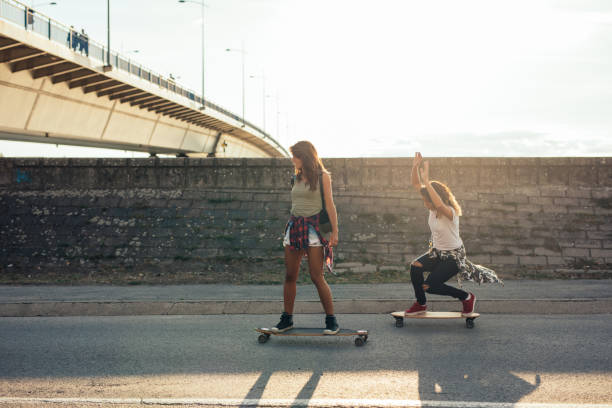 Skateboarding is awesome! Girls having fun riding skateboards outdoors. longboard skating photos stock pictures, royalty-free photos & images