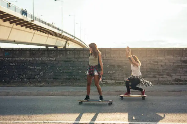 Girls having fun riding skateboards outdoors.