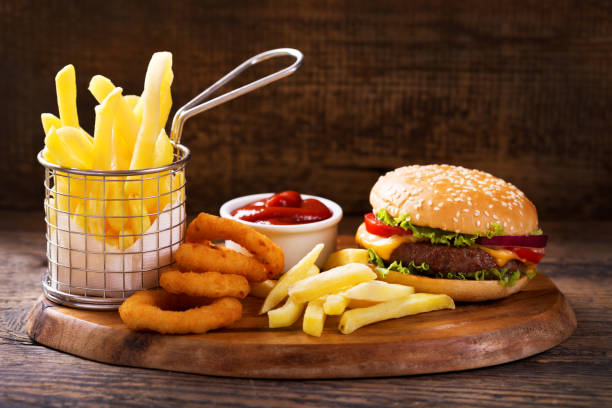 hamburger with french fries and onion rings hamburger with french fries and onion rings on wooden board fried onion rings stock pictures, royalty-free photos & images