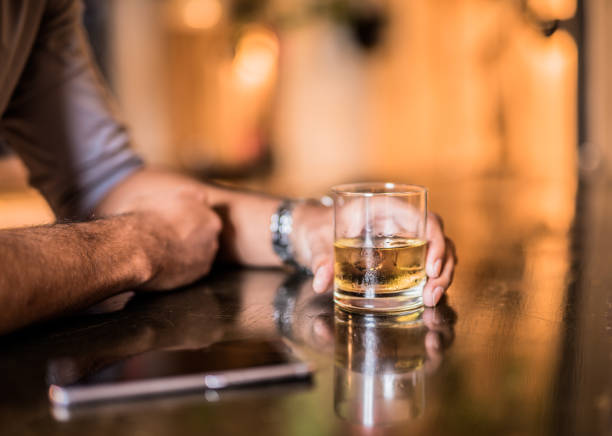 istock Young man holding his whiskey glass in the bar 865792114