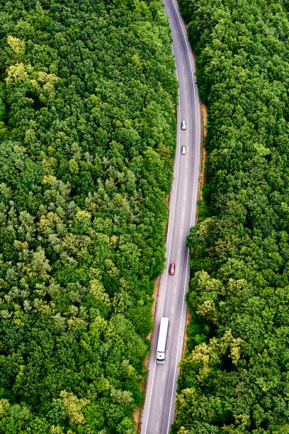 istock Aerial view over road with traffic going through forest landscape 865792848