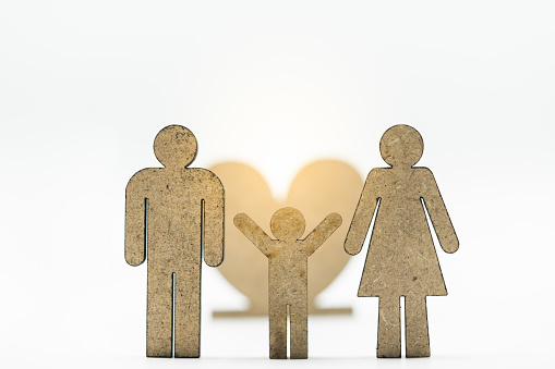 Wooden icon of parent and child together with heart as backdrop. Concept of family, parenthood, couple, and childhood.