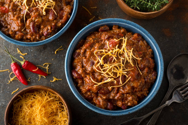 Chile A bowl of delicious home made chili with ground beef, kidney beans, red pepper, tomato and shredded cheddar cheese. ground beef photos stock pictures, royalty-free photos & images