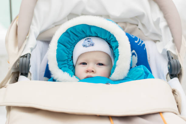 Baby in a perambulator (baby carriage) at a winter day Portrait of white european baby in winter clothes with hood with fur collar buggy eyes stock pictures, royalty-free photos & images