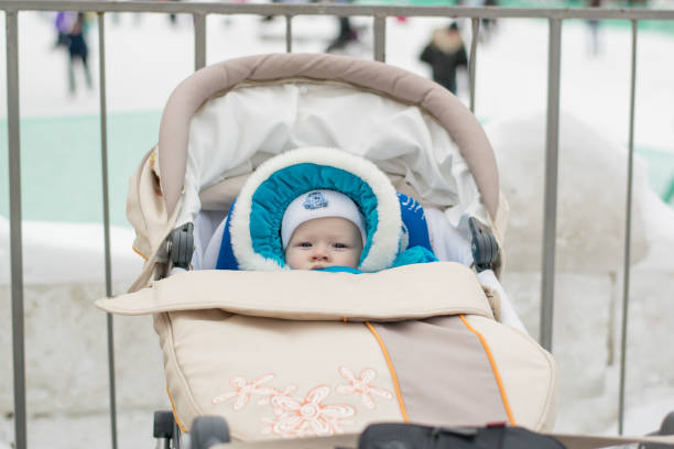 Baby in a perambulator (baby carriage) at a winter day Portrait of white european baby in winter clothes with hood with fur collar buggy eyes stock pictures, royalty-free photos & images