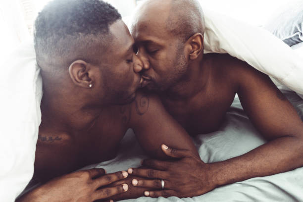 coppia gay baciare e fare sesso nel letto - homosexual beautiful sensuality love foto e immagini stock
