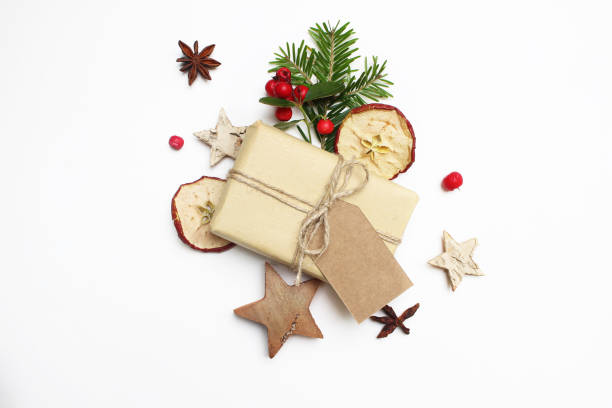 istock Christmas festive styled stock image composition. Handmade gift box with craft paper tag, berries, wooden stars, dried apples and fir tree branch on white wooden background. Flat lay, top view 865833074