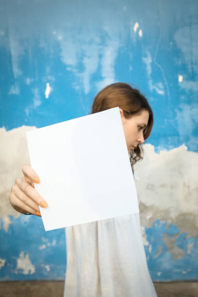istock Woman holding white blank paper 865833414