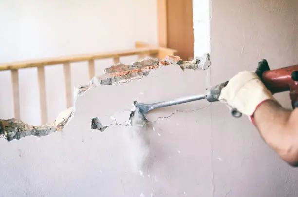 Construction worker using pneumatic hammer, construction site concept.