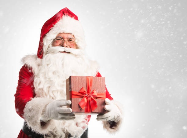 istock Santa Claus holding a present, giving away 865837132
