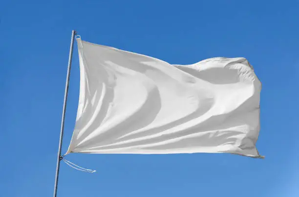 White flag attached to a flagpole waving on the sky