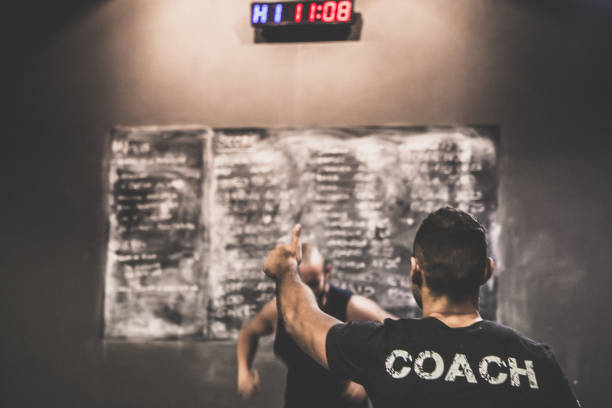 istock Cross training coach trains a guy in the gym, behind the points board, 865839624