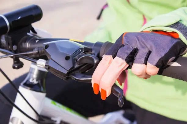 Photo of Woman's hand with bright nail Polish on the Bicycle wheel.