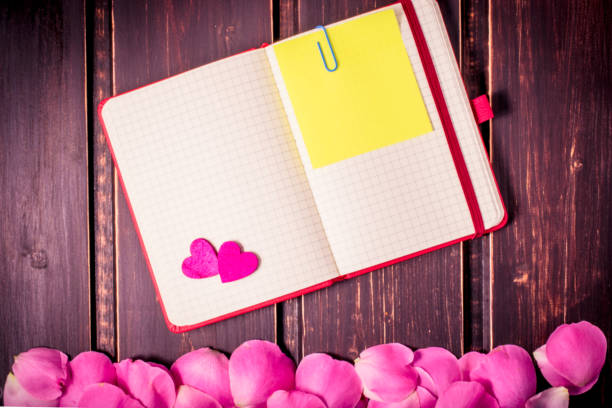 istock blank note book close-up with rose leaves, hearts and copy space on wooden background. Spring summer border template. mockup floral background. sale, greeting and celebration card concept. 865844202