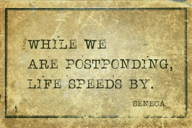 While we are postponding, life speeds by - ancient Roman philosopher Seneca quote printed on grunge vintage cardboard