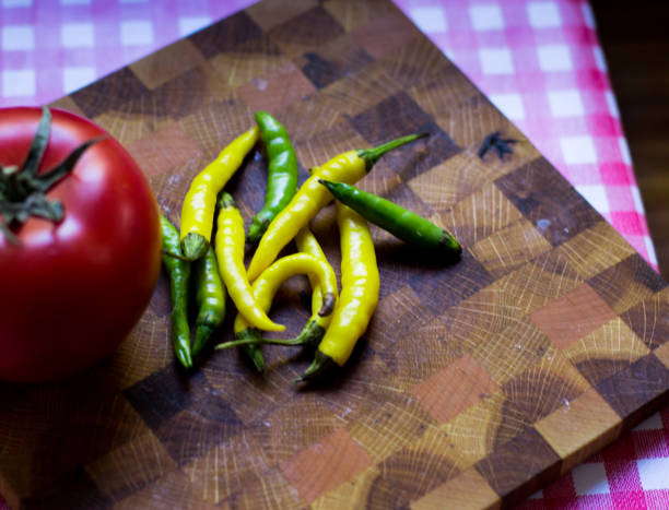 istock Chilli peppers and a red tomato on a cutting board 865857678