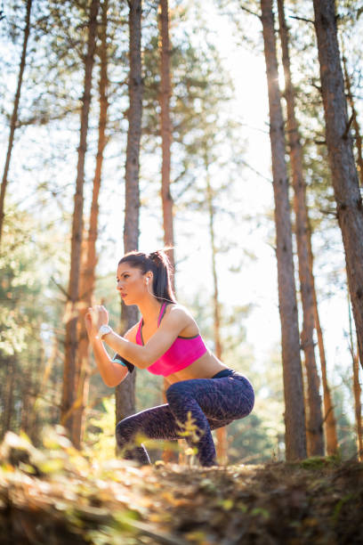 istock Young beautiful woman doing squats in the forest 865860178