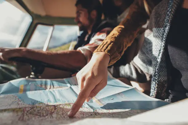 Photo of Friends on road trip using map for directions