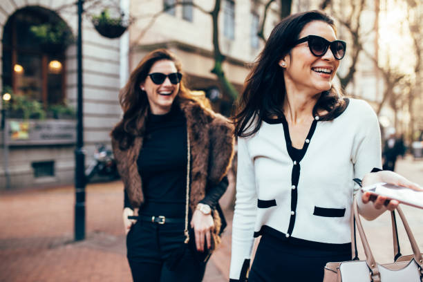 Two women on city street having fun Two women on city street having fun. Female friends on walking down the road and smiling outdoors. luxury lifestyle stock pictures, royalty-free photos & images