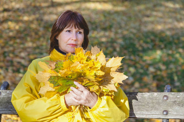 istock Beautiful older woman holding fallen maple leaves 865866968
