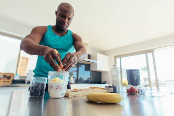 homme prépare le petit déjeuner dans la cuisine - smoothie banana smoothie milk shake banana photos et images de collection