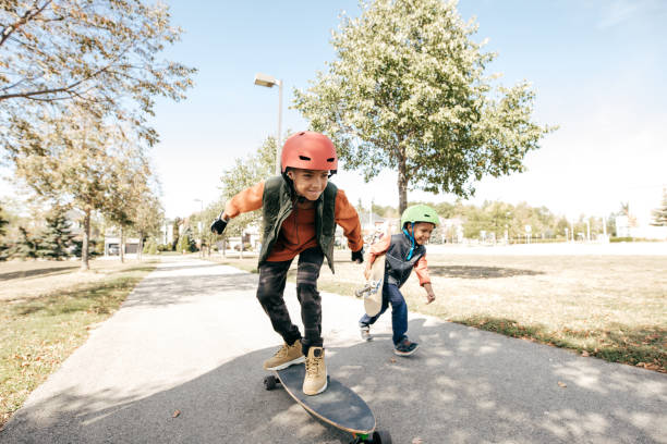 братья и сестры весело провести время с лонгбордом - skateboarding стоковые фото и изображения