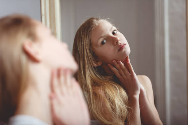 Reflection in mirror of teenage girl Teenage girl checking her face and body in the mirror sheepish look stock pictures, royalty-free photos & images
