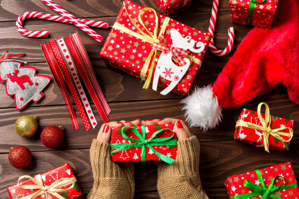 istock Woman holding Christmas gift over wooden table 865893644