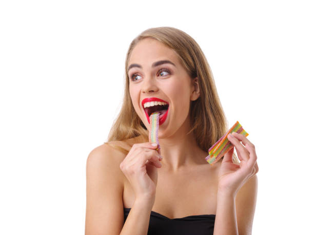 istock Young woman eating a colored sticky candy. Isolated on white background. 865900066