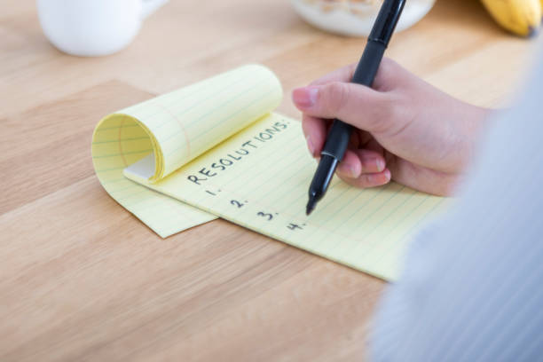 istock Unrecognizable woman makes list of resolutions during snack break 865900116