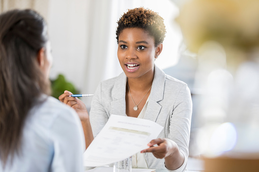 Young businesswoman has a serious expression on her face while discussing a document with a female colleague.