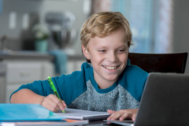 istock Cheerful schoolboy works on homework 865900382