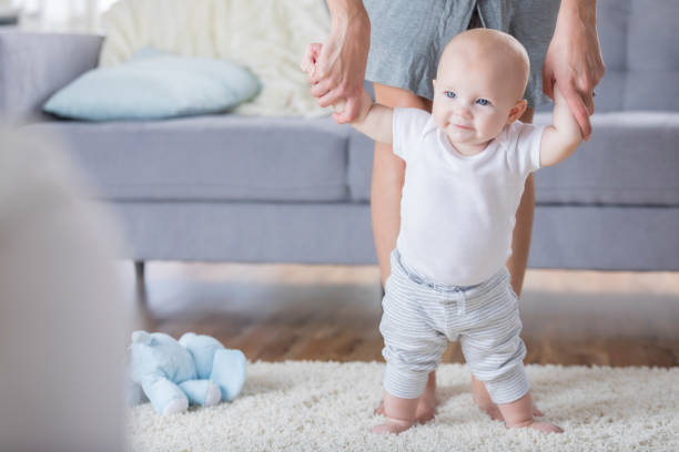 istock Cute baby walks with assistance at home 865900642