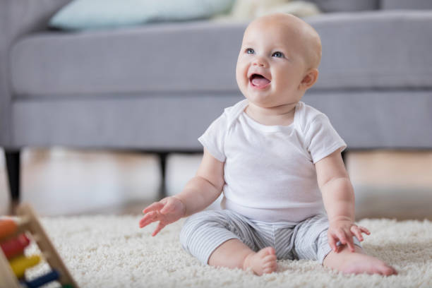 istock Adorable smiling baby sitting on floor and looking up 865900660