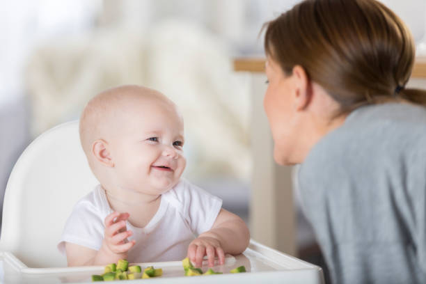 Little baby boy having piece of bread indoors