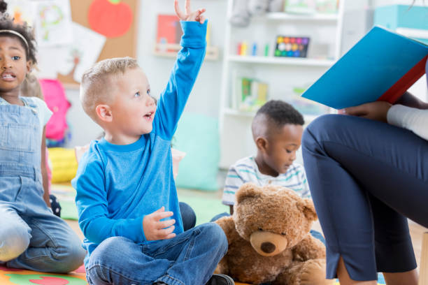 istock Little boy raises hand to ask a question in preschool classroom 865903192